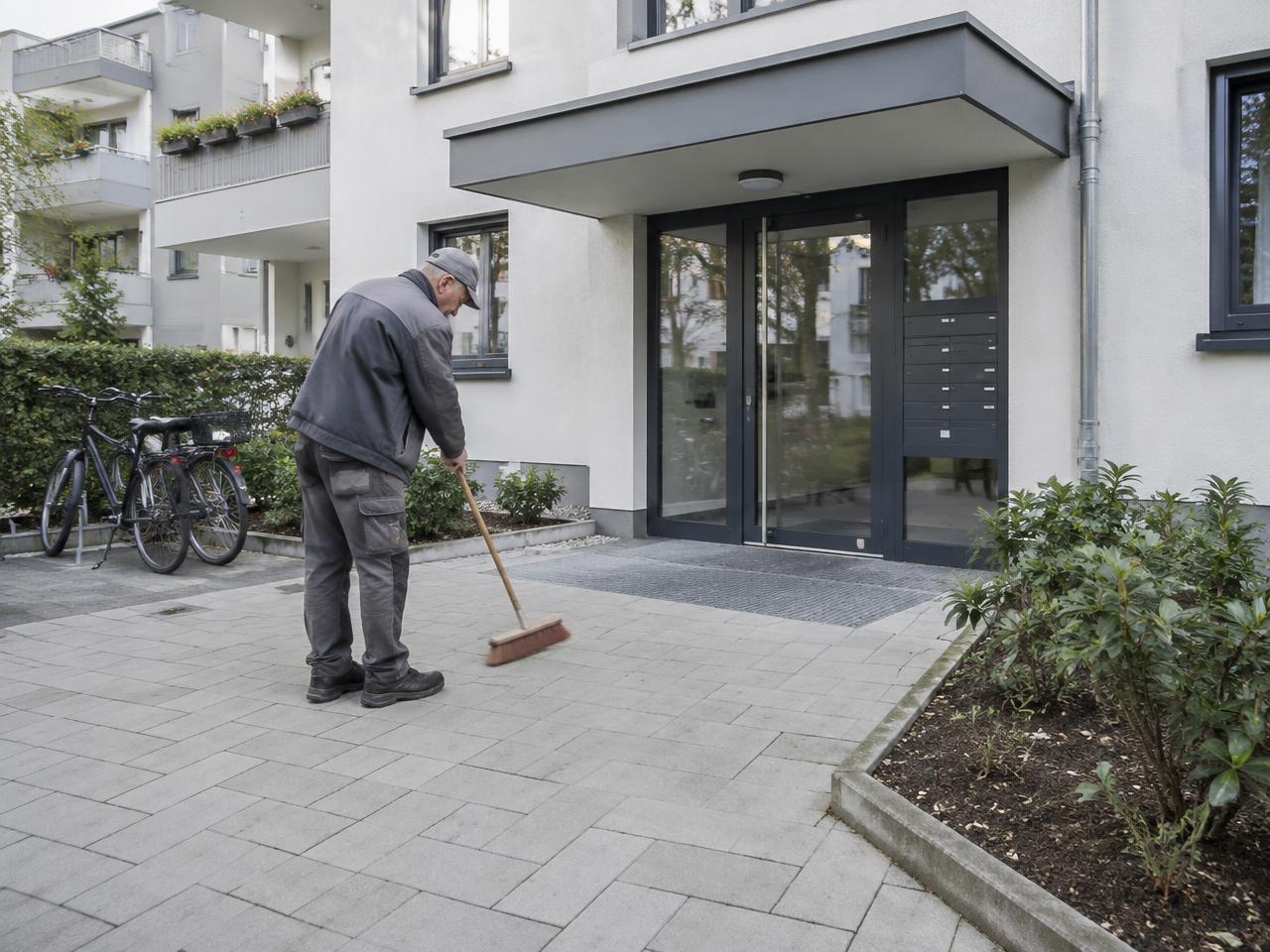 Hausmeister bei der Pflege des Eingangsbereichs eines Wohnhauses
